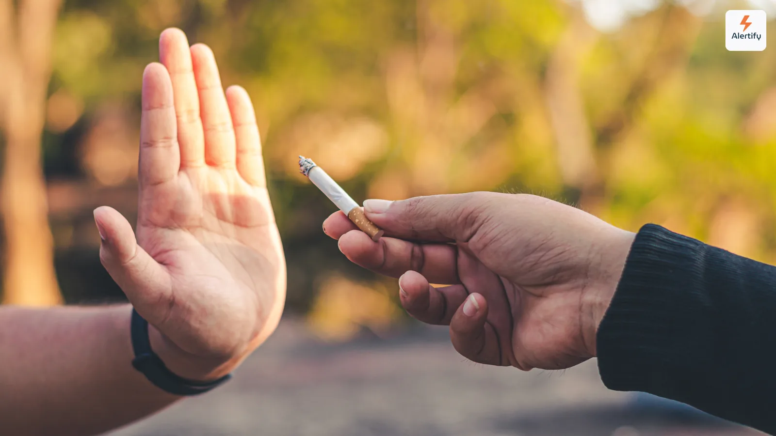 Erhobene Hand lehnt höflich eine angebotene brennende Zigarette einer anderen Person im Freien ab