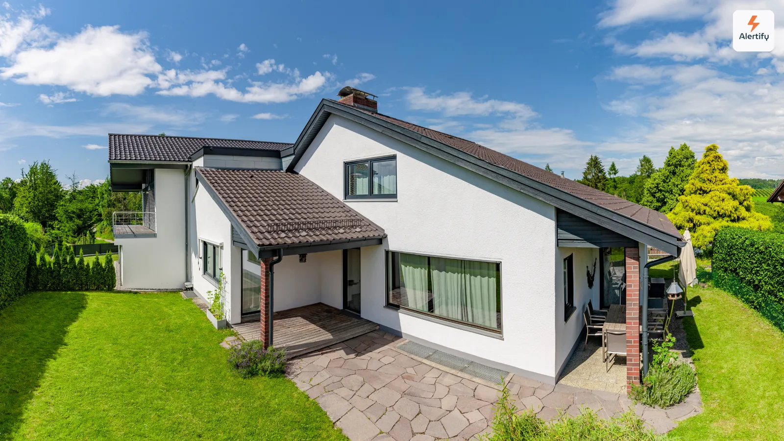 Leerstehendes weißes Einfamilienhaus mit Rasen und Terrasse zwischen zwei Mietverhältnissen